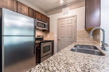 A kitchen with granite countertops and stainless steel appliances.